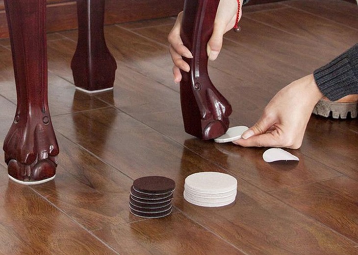 A person putting self adhesive furniture protectors 