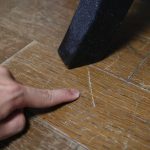 A person showing a scratch on the floor from the furniture