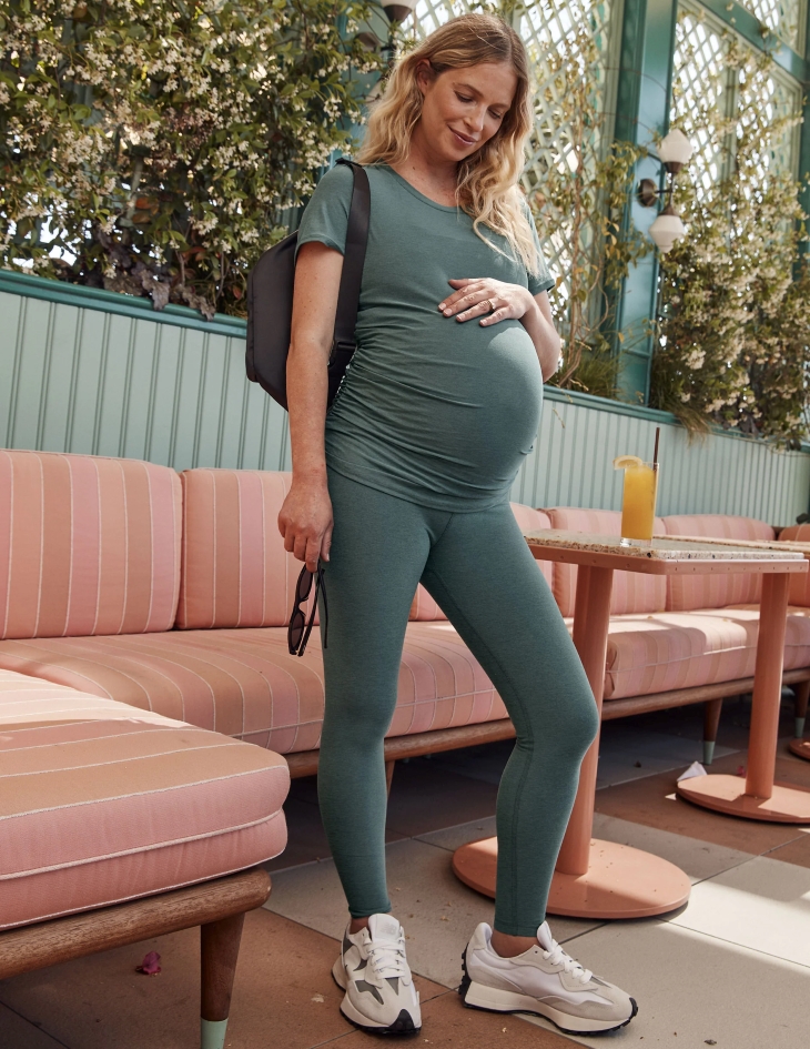 pregnant woman wearing maternity leggings, tshirt, sneakers and bag